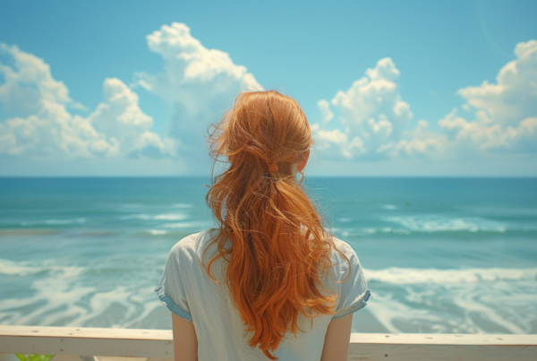 A woman with long red hair is standing on a balcony, looking out at the ocean. She is wearing a white shirt and appears to be deep in thought as she gazes at the vast expanse of the sea. The woman''s hair cascades down her back, adding a vibrant pop of color to the serene scene. The blue sky and water create a peaceful backdrop for her contemplation. The image captures a moment of introspection and connection with nature, as the woman takes in the beauty of the ocean view.
