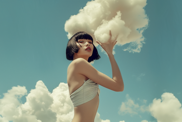 A woman in a bikini is standing outdoors, holding a cloud in the air. The woman has a youthful appearance, likely in her early twenties, with short hair and a large bust. She is confidently posing with the cloud, which adds a whimsical and dreamy element to the scene. The woman''s face and shoulders are the focus of the image, exuding a sense of serenity and beauty. The colors in the image are primarily shades of green and beige, creating a calm and natural atmosphere. The overall composition suggests a sense of freedom and connection to nature.