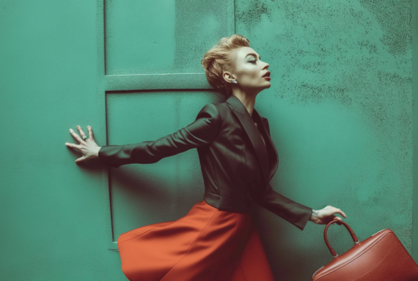 A woman is depicted in the image, leaning against a vibrant green wall. She is wearing a black dress and has her arms outstretched. The woman is carrying a stylish red handbag. The scene is set against a backdrop of a beautifully colored door. The image exudes elegance and style, with the woman''s outfit complementing the surroundings perfectly. The colors in the image include shades of green, red, and brown, creating a visually appealing composition. The overall vibe of the image is fashionable and chic, making it a great addition to a fashion or lifestyle dataset.