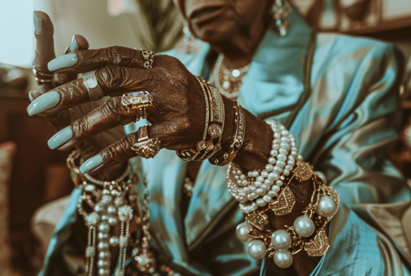 A woman is shown with jewelry on her hand, including a ring and bracelet. The image is focused on her hand, with the ring prominently displayed on her finger. The bracelet wraps around her wrist, adding a touch of elegance to her outfit. The woman is wearing other accessories as well, such as a necklace and possibly a tiara or crown. The background is blurred, drawing attention to the intricate details of the jewelry. Overall, the image exudes a sense of luxury and sophistication, with the woman''s hand adorned with beautiful pieces of jewelry.