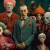 The image shows a group of people wearing clown costumes and clown heads. In the center, there is a man in a suit standing next to a woman dressed in a clown costume. The man is wearing a bow tie and has a serious expression on his face. Surrounding them are various other individuals, some wearing hats and others holding stuffed toys. The scene is playful and whimsical, with a mix of colors and textures. Some of the individuals have joker masks and there are sculptures scattered throughout the composition. The overall atmosphere is one of fun and eccentricity, with a touch of creepiness from the clown elements.