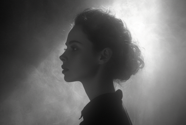 In the black and white photo, a woman with a very long hair is depicted wearing a black shirt and a black tie. She has a serious expression on her face and is standing against a dark background. The image focuses on the woman''s upper body, highlighting her black attire. The woman is the main subject of the photo, with her dark clothing contrasting against the light background. She exudes a sense of sophistication and elegance with her outfit choice. The photo captures her in a moment of contemplation or deep thought, adding a mysterious and intriguing element to the image.
